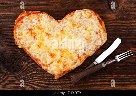 Una deliziosa pizza a forma di cuore sul tavolo di legno, vista dall'alto. Culinario mangiare pizza. Mi piace la pizza. Foto Stock