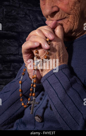 Nonna pregando. Vecchio rugoso bella donna di preghiera con il santo Rosario. La fede, spiritualy e religione. Foto Stock