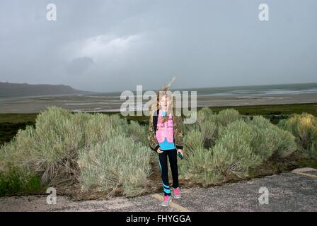 Giovane ragazza in piedi dalla spazzola con una tempesta di avvicinamento e i venti sono veramente soffiando i capelli in tutto. Foto Stock