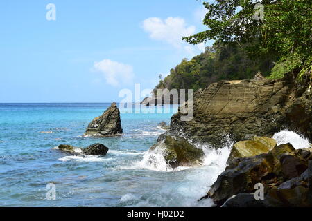 Onde che si infrangono contro gli scogli in inglese's Bay, Tobago. Foto Stock