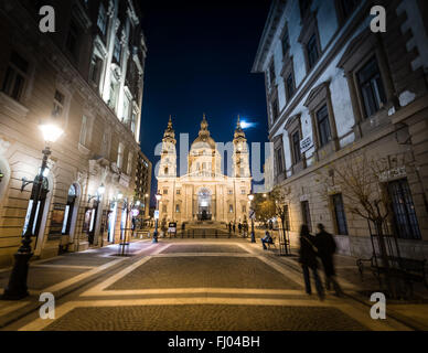 Scena notturna con Santo Stefano Chiesa nella parte Pest della città di Budapest, Ungheria, l'Europa. Le persone in primo piano e la cattedrale in backgr Foto Stock