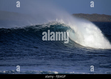 Grandi tubi blu onda con spray sopra la spalla e colline in background Foto Stock