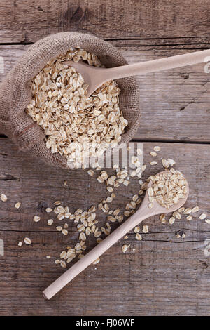 Borsa di avena e un cucchiaio di legno su sfondo di legno Foto Stock