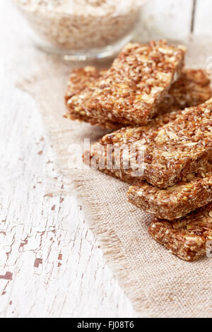 Barrette di cereali, fiocchi d'avena, semi di lino su uno sfondo di legno Foto Stock