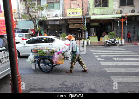 Un uomo spinge un carrello pieno di shopping in, China Town, Bangkok, Thailandia Foto Stock