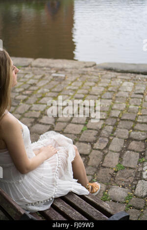 La donna si sedette sul banco di lavoro dal canale Foto Stock