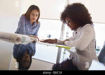 Team di due architetti femmina, seduto alla scrivania in ufficio. Le donne parlare rivedendo il progetto di un edificio. Riflessioni sulla tabella Foto Stock