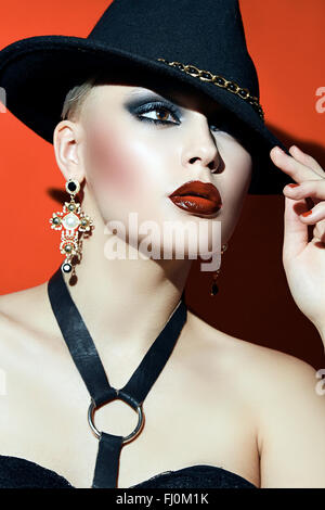 Rock Girl in un cappello nero con labbra rosse e occhi scuri in un corsetto.
