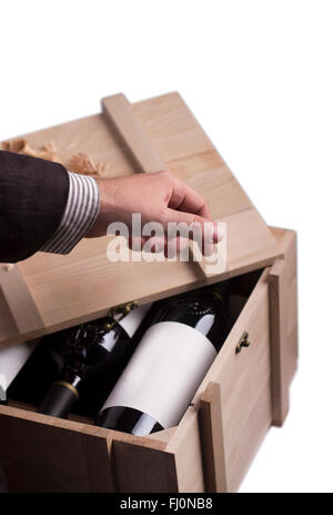 Una mano scegliendo una bottiglia di vino proveniente da una gabbia in legno Foto Stock