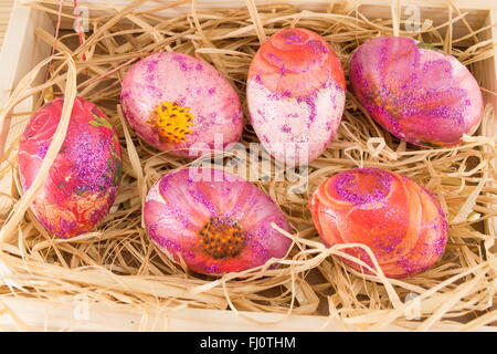 Decoupage decorate le uova di pasqua in una scatola di legno riempita di paglia Foto Stock