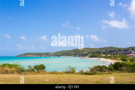 Vista della incontaminata e popolare spazzare Dickenson Bay Beach a nord di Antigua Antigua e Barbuda, West Indies sotto il cielo blu Foto Stock