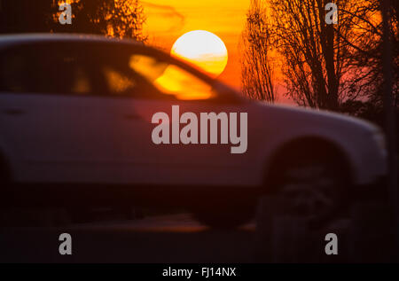 La sfera rossa del sole al tramonto è distorto dalle finestre di un passaggio auto, in Frankfurt am Main, Germania, 27 febbraio 2016. Foto: FRANK RUMPENHORST/DPA Foto Stock