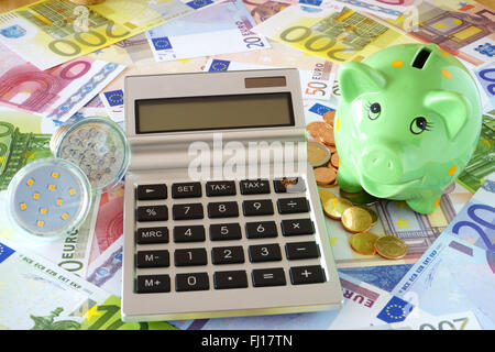 Calcolatrice tascabile con display vuoto, lampade a LED, verde salvadanaio su uno sfondo costituito delle banconote e delle monete in euro Foto Stock