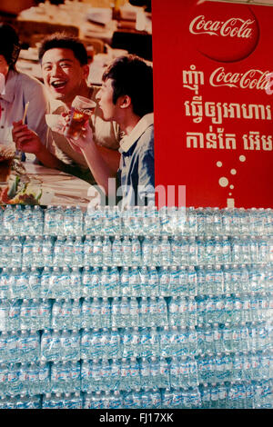 Le bottiglie di plastica sono impilati sotto un grande Coca Cola pubblicità segno in un ristorante Skun, Kampong Cham provincia, in Cambogia. Foto Stock