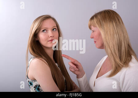 Ragazza adolescente di essere rimproverato da sua madre che sta puntando il dito a sua figlia Foto Stock