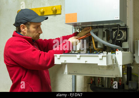 Plumber riparazione di una caldaia a condensazione nella sala caldaie Foto Stock