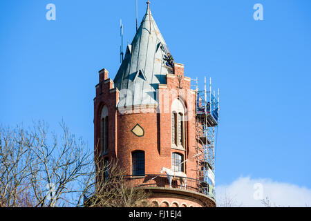 Ronneby, Svezia - 26 Febbraio 2016: alta altitudine riparazioni sul tetto della vecchia torre di acqua in città. Una persona è in v Foto Stock