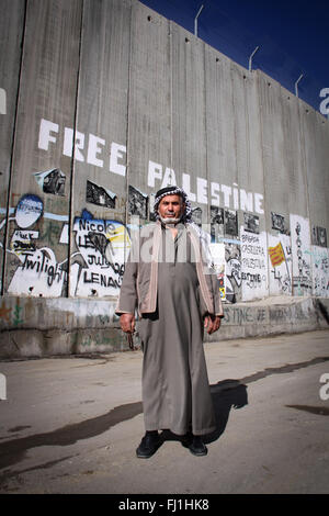 Un uomo palestinese sta al checkpoint di Betlemme nella parte anteriore della parete di separazione Foto Stock