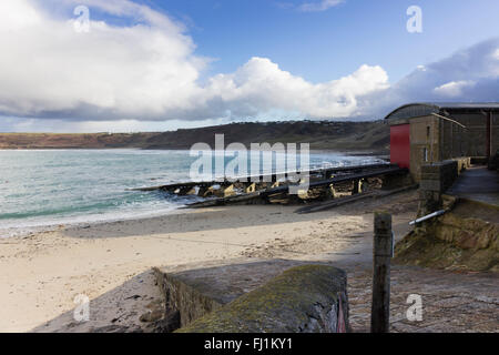 Sennen Cove scialuppa di salvataggio stazione con rampe di lancio contro un ritardo deserta spiaggia invernale e cielo tempestoso Foto Stock