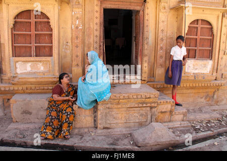 Le donne sono la discussione all'entrata di haveli / casa con architettura tradizionale in Jaisalmer , Rajasthan, India Foto Stock