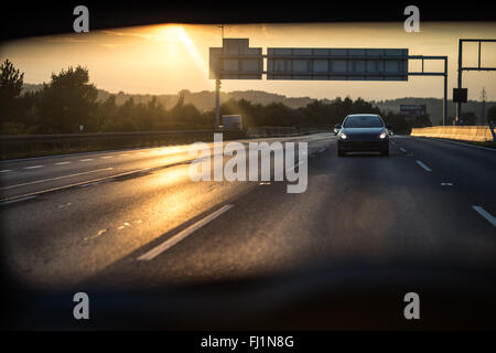 Automobili su una autostrada al tramonto (SHALLOW DOF; dai toni di colore immagine) Foto Stock