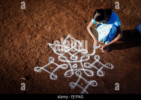 La donna è il disegno rangoli di fronte alla sua casa nella luce del mattino in Hampi, India Foto Stock