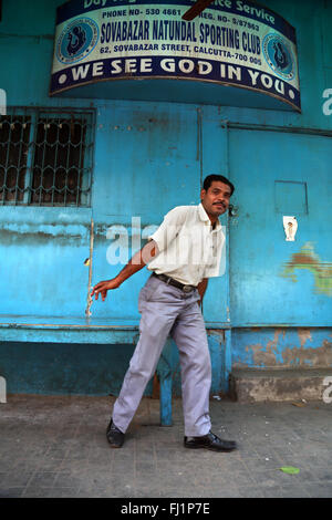 Un uomo si erge in Kolkata sotto una scheda dove la scritta 'Vediamo Dio in voi" Foto Stock