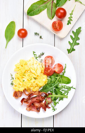 La prima colazione con uova strapazzate, bacon e insalata di verdure, vista dall'alto Foto Stock