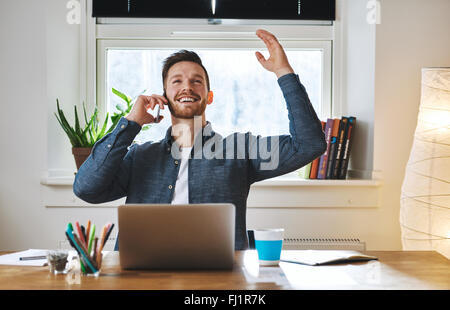 Imprenditore di successo cercando felice seduto alla scrivania con le braccia sopra la testa Foto Stock