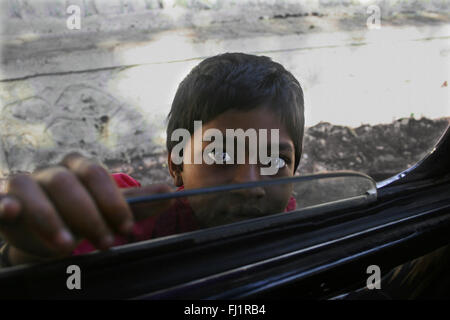 Ragazza giovane mendicante in taxi in finestra il traffico di Mumbai, India Foto Stock