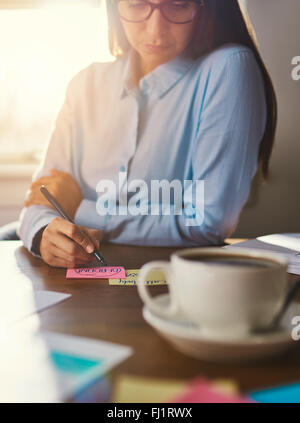 Imprenditore femmina la scrittura di note alla scrivania, business donna guardare Foto Stock