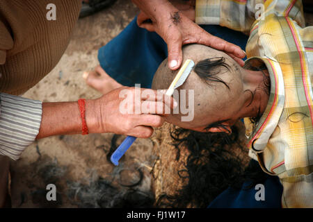 Rituale di rasatura per pellegrina su un ghat di Varanasi, India Foto Stock