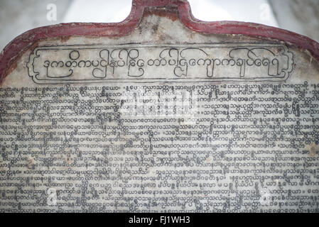 L'iscrizione in stele di marmo della Pagoda di Kuthodaw Mandalay Myanmar // MANDALAY, Myanmar — Una lastra di marmo con inciso il testo di Pali fa parte del "libro più grande del mondo" presso la Pagoda di Kuthodaw (nota anche come Kuthodaw Paya). Questo dettaglio mostra una delle 729 stele di marmo, ciascuna incisa su entrambi i lati con scritture buddiste del Tipitaka (canone Pali). Create tra il 1860 e il 1868 sotto la direzione del re Mindone, queste tavolette di marmo sono alloggiate individualmente in piccoli stupa bianchi chiamati kyauksa GU (grotte di pietra) disposti in righe ordinate all'interno del complesso pagoda. Le iscrizioni erano originariamente W Foto Stock