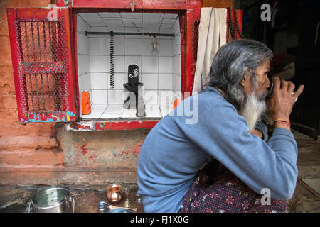 L uomo beve tè in Varanasi, India , nella parte anteriore del tempio di Shiva lingam Foto Stock