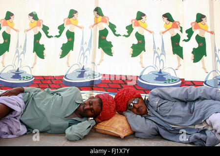 Due uomini stanno dormendo con turbante durante il Pushkar mela camel fair , Rajasthan Foto Stock