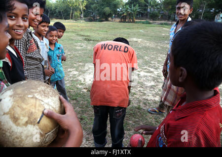 Sorridenti bambini a giocare a calcio con 'WORLD' t shirt in Sreemangal , Bangladesh Foto Stock