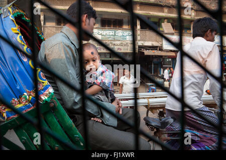 Un giovane bambino viaggia con il padre nel traffico a Dhaka in tradizionale rickshaw , Bangladesh Foto Stock