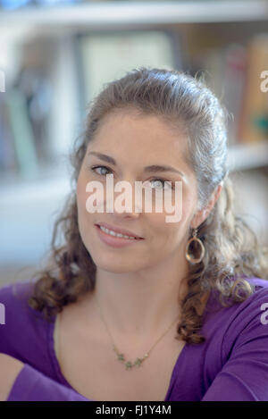 Giovane donna con libro scaffali in background Foto Stock