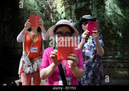 I turisti tenendo selfie con telefono cellulare all'interno di Angkor Vat tempio, Cambogia Foto Stock