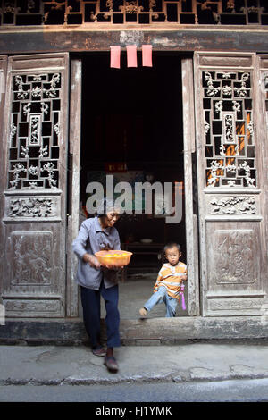 Vecchia donna e bambino attraverso la vecchia porta del tempio nel villaggio di Pingyao, Cina Foto Stock