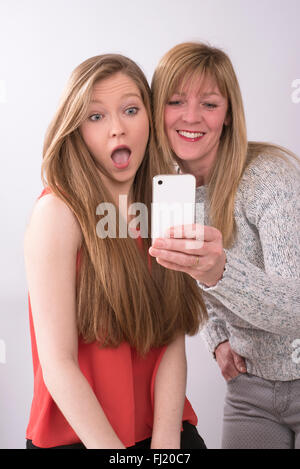 Ritratto espressivo di madre e figlia utilizzando un telefono cellulare Foto Stock