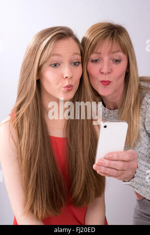 Ritratto espressivo di madre e figlia utilizzando un telefono cellulare Foto Stock