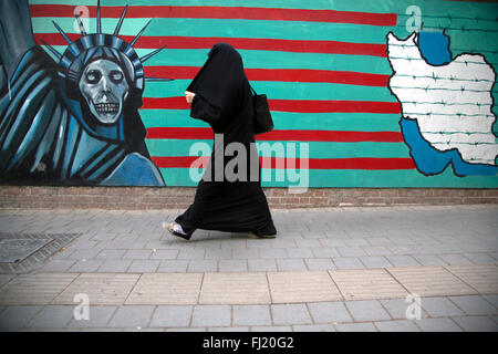 Una donna cammina lungo un suggestivo murale sulla parete della ex ambasciata USA / Stati Uniti Den di spionaggio a Tehran, Iran Foto Stock