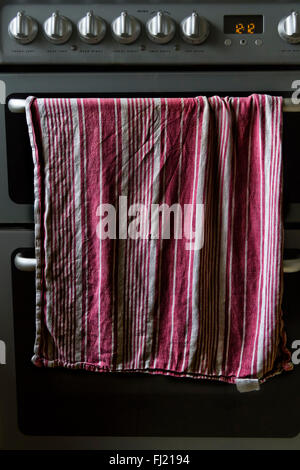 Tovagliolo o Asciugando panno appeso sulla porta di un forno maniglia di un fornello domestico Foto Stock