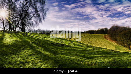 Il bellissimo panorama di un paesaggio rurale in Germania, colline, erba verde, blu cielo e imminente raggi di sole. Foto Stock