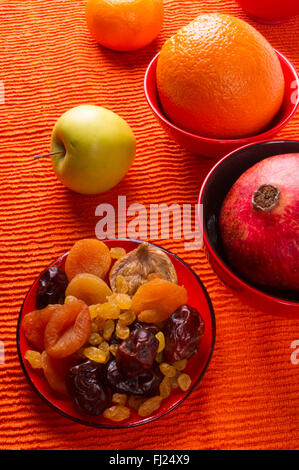 Secchi e frutta fresca sul tessuto sfondo arancione Foto Stock