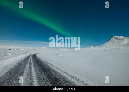 Le luci del nord in ballo nel cielo sopra un congelate di strada di montagna Foto Stock
