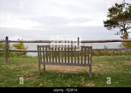 Panca in legno su erba verde che si affaccia sul foggy Long Island Sound a Long Island, NY, STATI UNITI D'AMERICA. Foto Stock