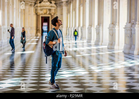 Corpo pieno colpo di un ragionato bel giovane, tenendo una guida, guardando lontano all interno di un museo Foto Stock