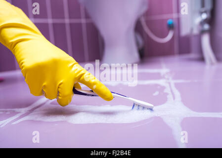 Pulire le piastrelle con uno spazzolino da denti. Foto Stock